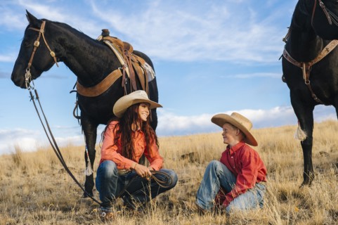 Caucasian mother and son with horses in grassy field