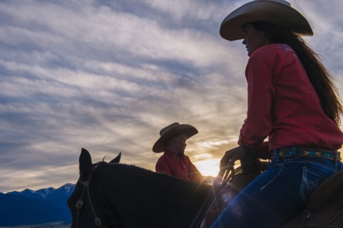 Caucasian mother and son riding horses at sunset