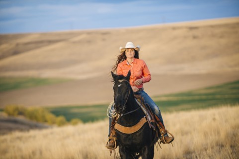 Caucasian woman riding horse in grassy field