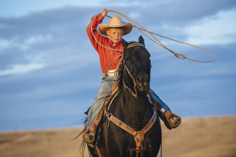 Caucasian boy on horse throwing lasso