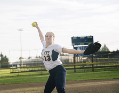 Caucasian softball player pitching ball in field