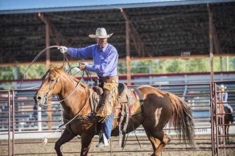 Older Caucasian cowboy throwing lasso at rodeo
