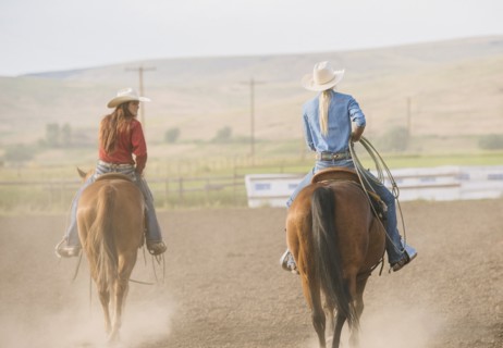 Caucasian cowgirls riding horses on ranch