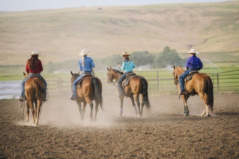 Cowgirls and cowboy riding horses on ranch