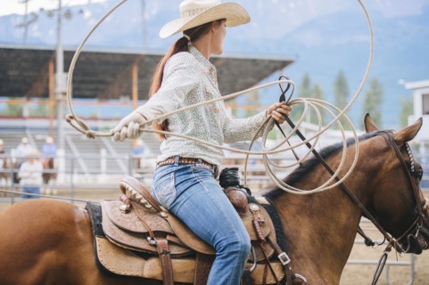 Caucasian cowgirl twirling lasso in rodeo