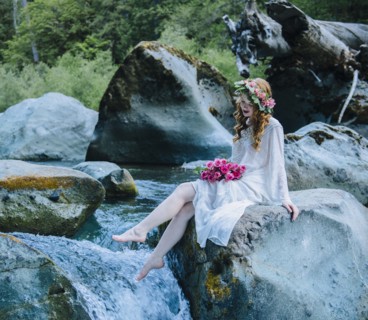 Caucasian woman wearing flower crown on rock at river waterfall