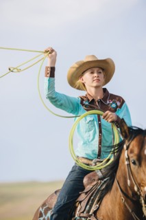 Caucasian cowgirl throwing lasso on horseback