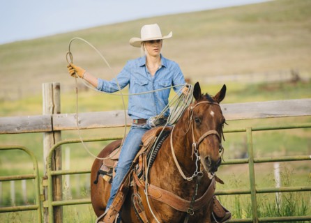 Caucasian cowgirl throwing lasso on horseback
