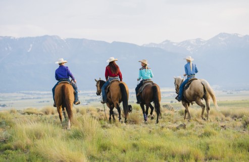 Cowboy and cowgirls riding horseback on ranch