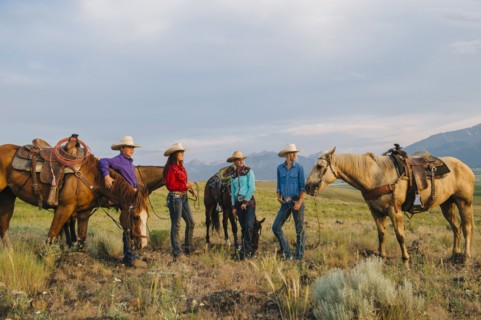 Cowboy and cowgirls with horses on ranch