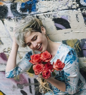 Laughing Caucasian woman at graffiti wall holding flowers