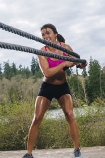 Mixed Race woman working out with heavy ropes