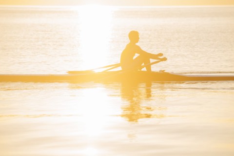 Silhouette of Caucasian man rowing on lake