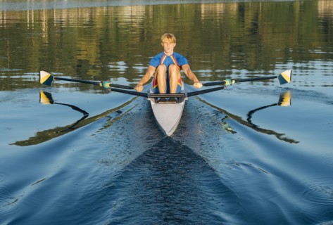 Caucasian man rowing on river