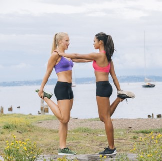 Women stretching legs near lake
