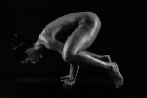 Naked muscular Mixed Race woman balancing on hands