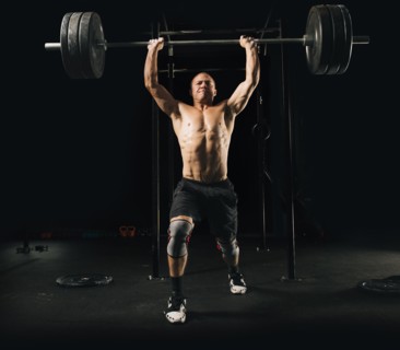 Man lifting heavy barbell in gymnasium