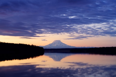 Reflection of clouds and mountain in river at sunset