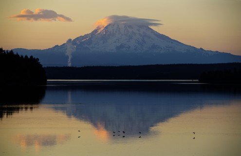 Reflection of clouds and mountain in river at sunset