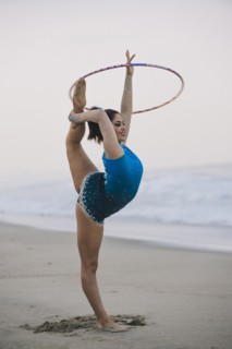 Caucasian gymnast practicing with hoop on beach