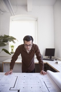 Hispanic businessman looking at blueprints