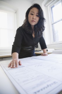 Asian businesswoman looking at blueprints