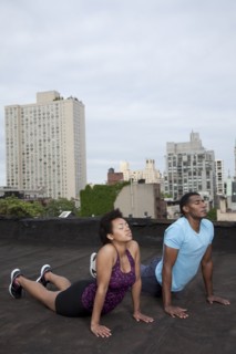 African American couple practicing yoga on rooftop