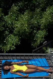 Black woman sunbathing on fire escape