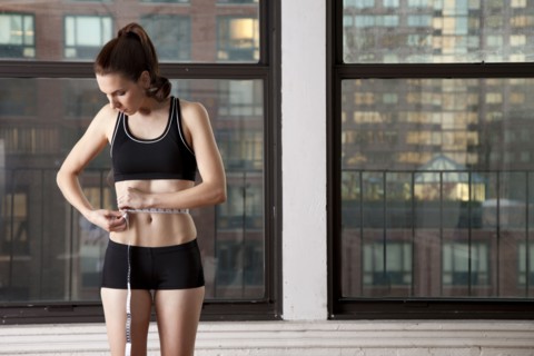 Caucasian woman measuring her waistline
