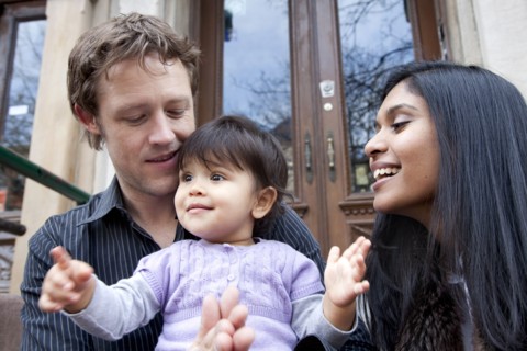 Parent's sitting on front stoop with baby girl