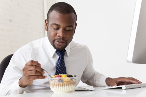Black businessman eating breakfast at desk