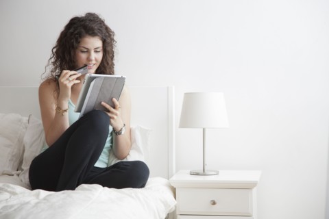 Caucasian woman using digital tablet in bed