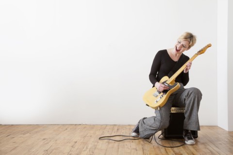 Caucasian woman playing electric guitar