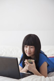 Chinese woman using laptop on bed
