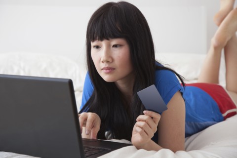 Chinese woman shopping online on bed