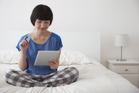 Chinese woman using tablet computer on bed