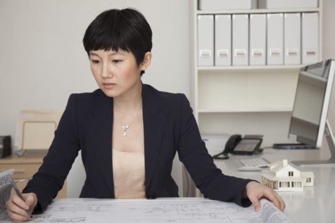 Businesswoman examining blueprints in office