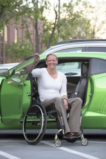 Disabled woman in wheelchair climbing into car
