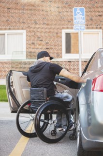 Disabled man in wheelchair climbing into car