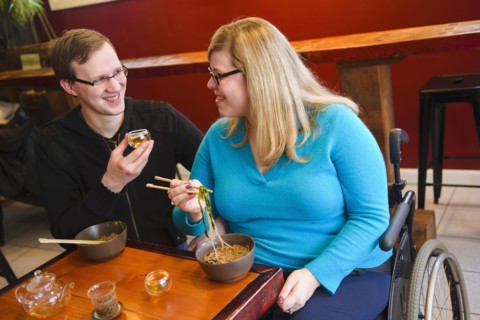 Paraplegic woman and boyfriend eating noodles in tea shop