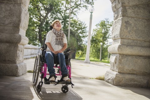 Paraplegic woman in wheelchair under stone arch