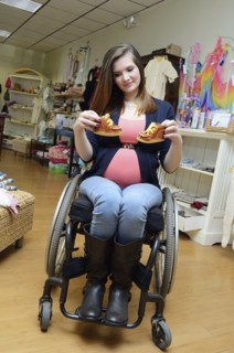 Pregnant paraplegic woman in wheelchair shopping in baby store