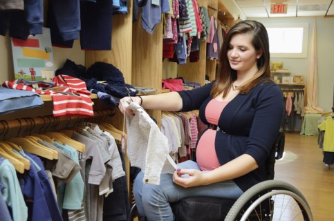 Pregnant paraplegic woman in wheelchair shopping in baby store