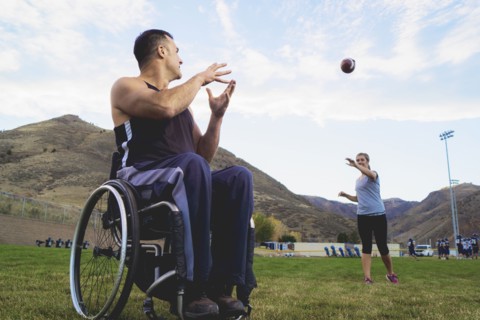 Paraplegic athlete in wheelchair with girlfriend tossing ball