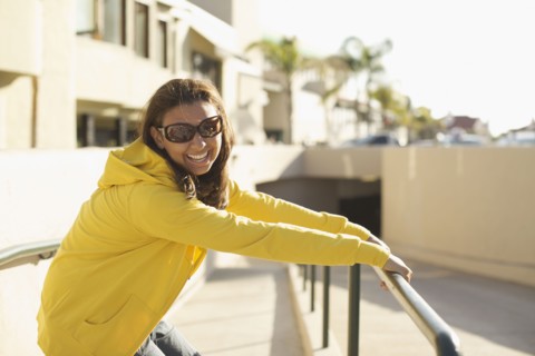 Mixed race woman in sunglasses leaning on railing