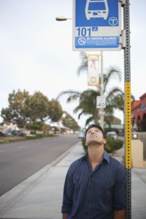 Mixed race man looking at bus stop sign
