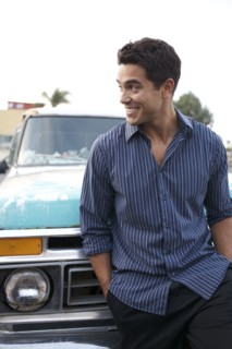 Mixed race man leaning against truck