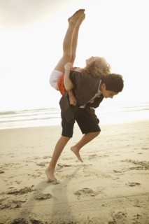 Boy lifting girl on back on beach