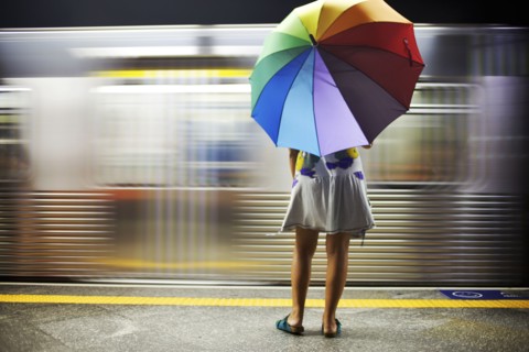 Mixed race woman with umbrella on train platform
