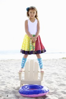 Mixed race girl standing on chair on beach